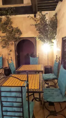 two tables and chairs in a room with a fireplace at Riad Sabbah in Marrakech