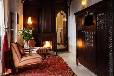 a living room with a fireplace and a couch and a chair at Riad Azzar in Marrakech