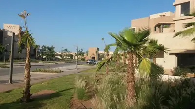 a street with palm trees in front of a building at Prestigia Golf City Apartment in Marrakech