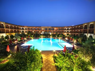 a large pool in front of a building at night at Ennakhil Marrakech Hotel & SPA in Marrakech