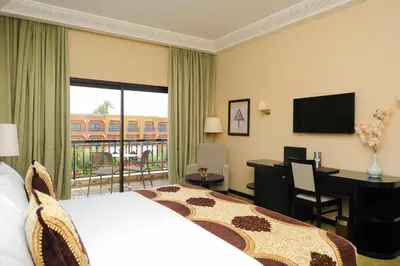 a hotel room with a bed and a desk with a computer at Ennakhil Marrakech Hotel & SPA in Marrakech