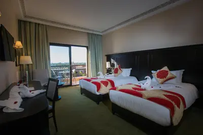 a hotel room with two beds and a window at Ennakhil Marrakech Hotel & SPA in Marrakech