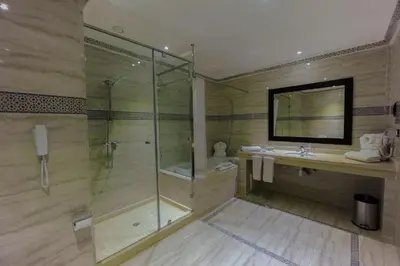 a bathroom with a glass shower and a sink at Ennakhil Marrakech Hotel & SPA in Marrakech