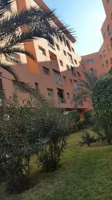 a large building with a palm tree in front of it at Kim Apartment in Marrakech