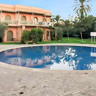 a villa with a swimming pool in front of a house at Comfortable Apartment in Marrakech with Shared Pool, 124 sqm in Marrakech