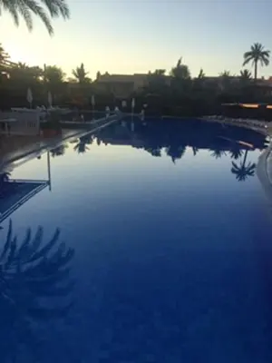 a large blue swimming pool with palm trees in the background at Comfortable Apartment in Marrakech with Shared Pool, 124 sqm in Marrakech