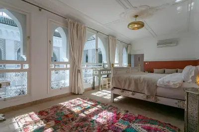 a bedroom with a bed and windows and a rug at Riad Zeitoun Palace in Marrakech