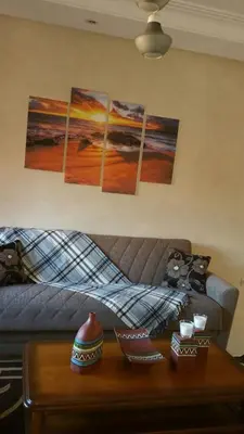 a living room with a couch with four paintings on the wall at Mouzdalifa Apartment In City Center in Marrakech