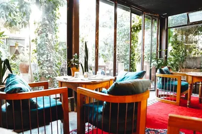 a restaurant with wooden tables and chairs and windows at La Ferme Medina in Marrakech