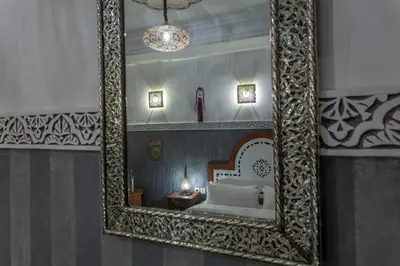 a mirror hanging on a wall with a bed in a room at Astra Damus Hotel in Marrakech