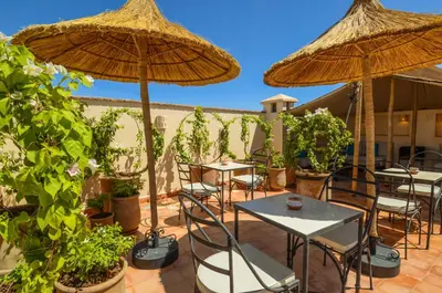a patio with tables and chairs and umbrellas at Riad Ayni in Marrakech