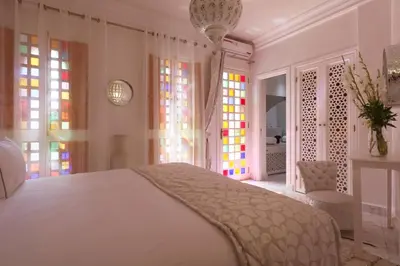 a bedroom with a white bed and stained glass windows at Riad Andallaspa in Marrakech