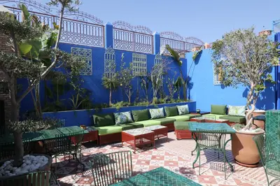 a patio with a couch and tables and a blue wall at Riad Andallaspa in Marrakech