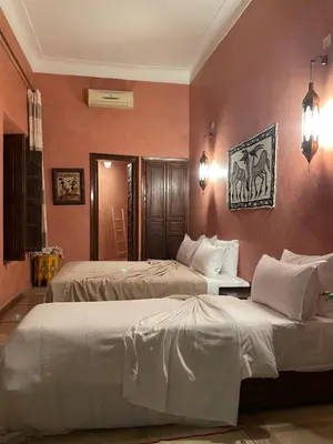 two beds in a room with pink walls at Riad Safia in Marrakech