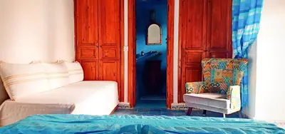 a bedroom with a bed and a chair and a door at Riad Safia in Marrakech