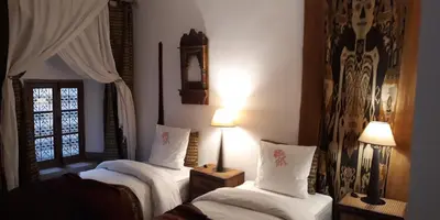 a bedroom with two beds with white sheets and a window at Riad Dar Oulhoum in Marrakech