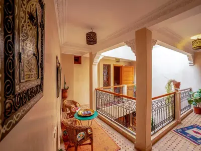 a hallway with a balcony with a table and chairs at Riad Majdoulina chez JIJI in Marrakech