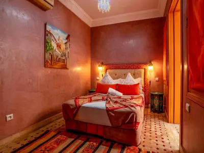 a bedroom with a bed with red pillows at Riad Majdoulina chez JIJI in Marrakech