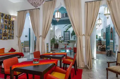 a living room with tables and chairs and curtains at Riad Azahar in Marrakech