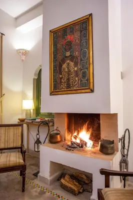a fireplace with a painting on the wall at Riad Azahar in Marrakech