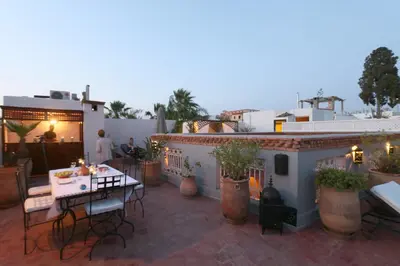 a patio with a table and chairs on a roof at Riad Merstane Marrakech in Marrakech