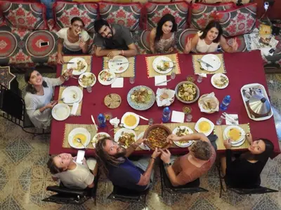 a group of people sitting around a table eating food at Kasbah Red Castel Hostel in Marrakech