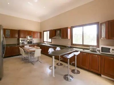 a kitchen with wooden cabinets and a table with chairs at Maison d'hote Oceania in Marrakech