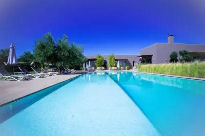 a large blue swimming pool with chairs and umbrellas at Villa Jardins D'Isa in Marrakech