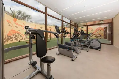 a gym with treadmills and ellipticals in a room with windows at Be Live Experience Marrakech Palmeraie - All Inclusive in Marrakech