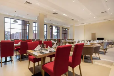a dining room with tables and red chairs at Be Live Experience Marrakech Palmeraie - All Inclusive in Marrakech
