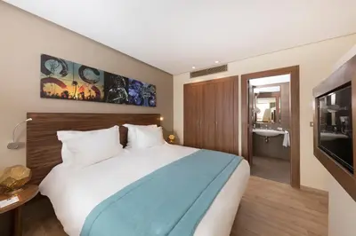 a hotel room with a large bed and a bathroom at Be Live Experience Marrakech Palmeraie - All Inclusive in Marrakech