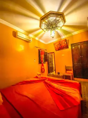 a large red bed in a bedroom with a chandelier at Riad Salma Restaurant Spa in Marrakech