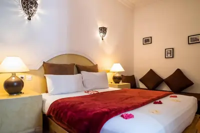 a bedroom with a large bed with a red blanket at Riad Al Tainam in Marrakech