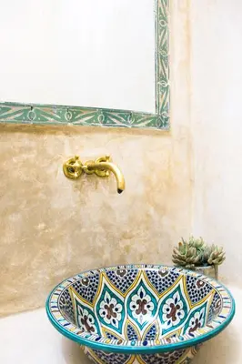 a bathroom sink with a gold faucet on a wall at Riad Al Tainam in Marrakech