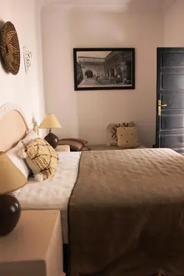 a bedroom with a bed and a table and a picture at Riad Al Tainam in Marrakech