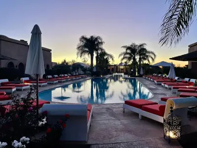 a large swimming pool with lounge chairs and an umbrella at Les Résidences Du Domaine in Marrakech