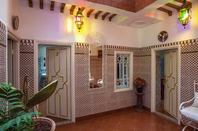 a living room with tiled walls and a mirror at Hotel Zitoune in Marrakech
