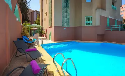 a large swimming pool with purple chairs next to a building at Appart-Hotel Amina Resort & Spa in Marrakech