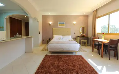 a bedroom with a bed and a kitchen and a table at Appart-Hotel Amina Resort & Spa in Marrakech