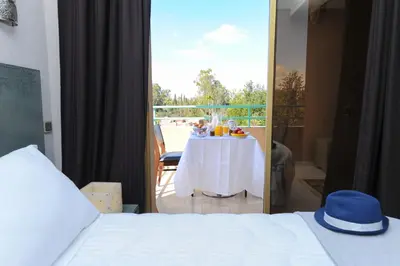 a bedroom with a table and a view of a balcony at Appart-Hotel Amina Resort & Spa in Marrakech