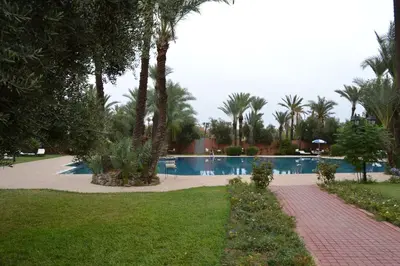 a swimming pool with palm trees in a park at In Club Palmeraie Resorts in Marrakech