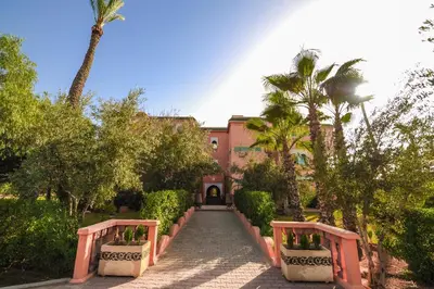 a pathway leading to a house with palm trees at In Club Palmeraie Resorts in Marrakech