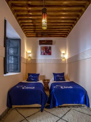 two beds in a room with blue sheets at Riad Ciel d'Orient in Marrakech