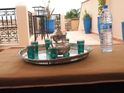 a tray with green cups on a table with a bottle at Riad Ciel d'Orient in Marrakech