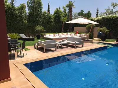 a backyard with a swimming pool with a patio furniture and an umbrella at Villa Riad Al Maaden in Marrakech