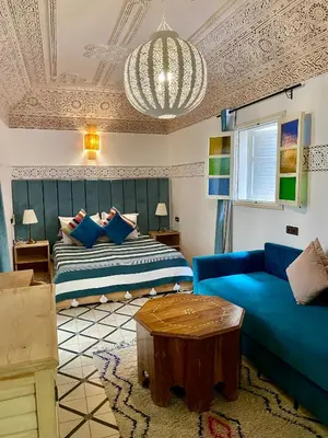 a living room with a bed and a blue couch at Riad Green Vines in Marrakech