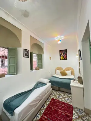 a bedroom with two beds and a rug at Riad Green Vines in Marrakech
