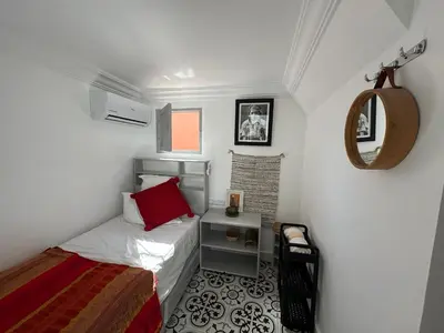 a small bedroom with a bed and a mirror at Riad Green Vines in Marrakech