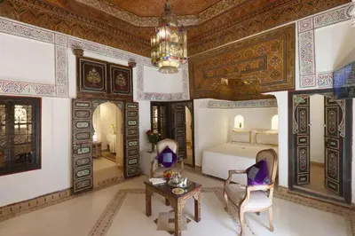a bedroom with a bed and a table and a chandelier at Riad Palais Des Princesses & Spa in Marrakech