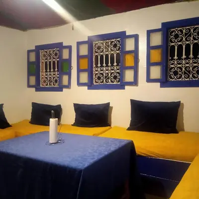 a room with two beds and a table with a candle on it at Riad Tifor in Marrakech